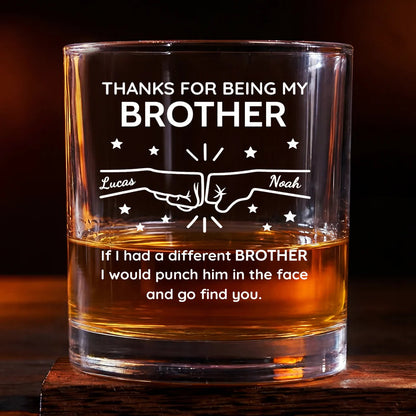 Personalized brother whiskey glass with custom names and a fist bump design containing amber liquid on a wooden surface